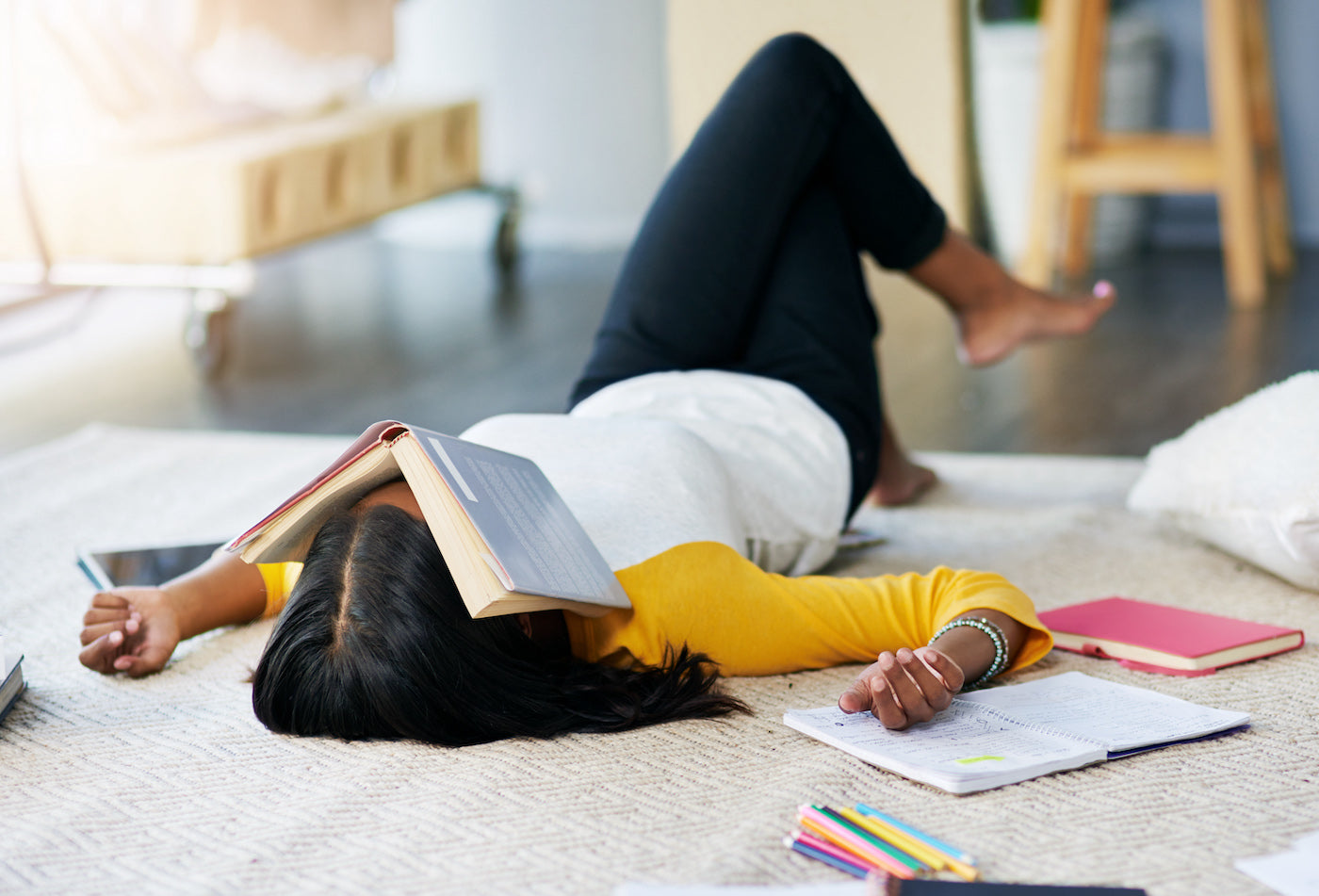 Student laying on floor with book over her face.