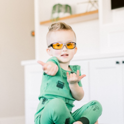 Boy in green pajamas playing while wearing TrueDark Superhero Daylights glasses