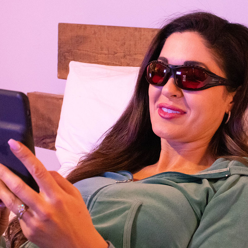 Woman Wearing TrueDark Twilight Classic Glasses while looking at her phone