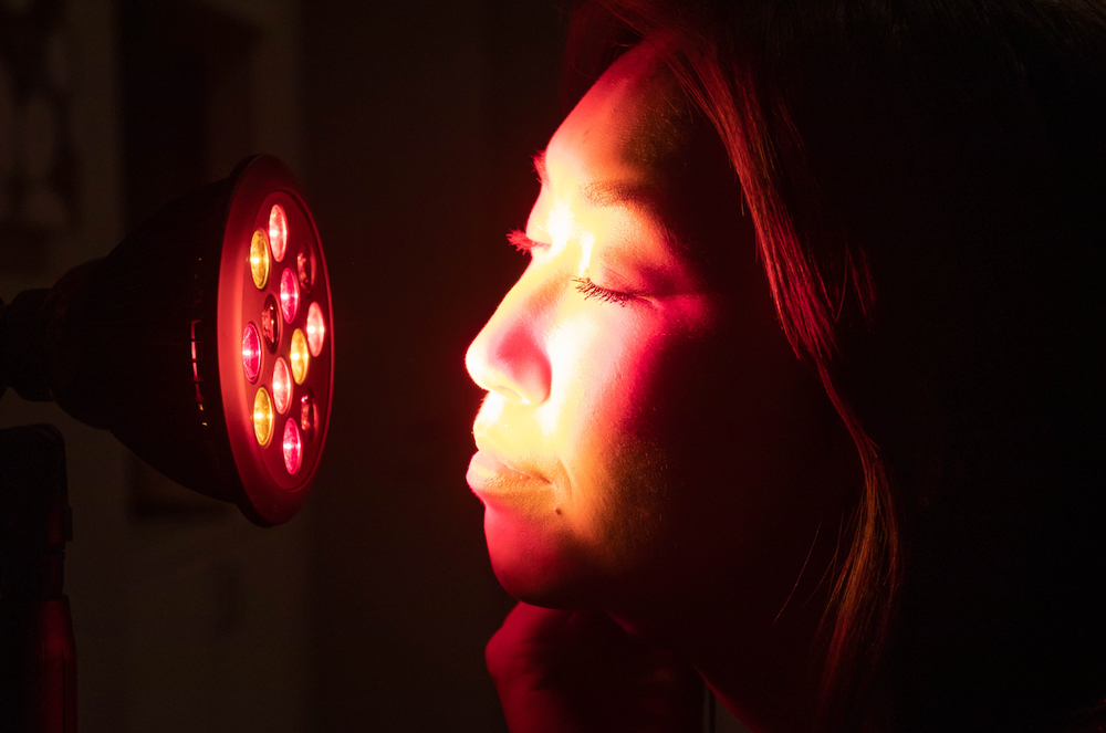 Woman using a TrueLight LED light therapy device on her face