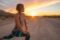Woman in yoga pants stretching before a run on a gravel road near sunset