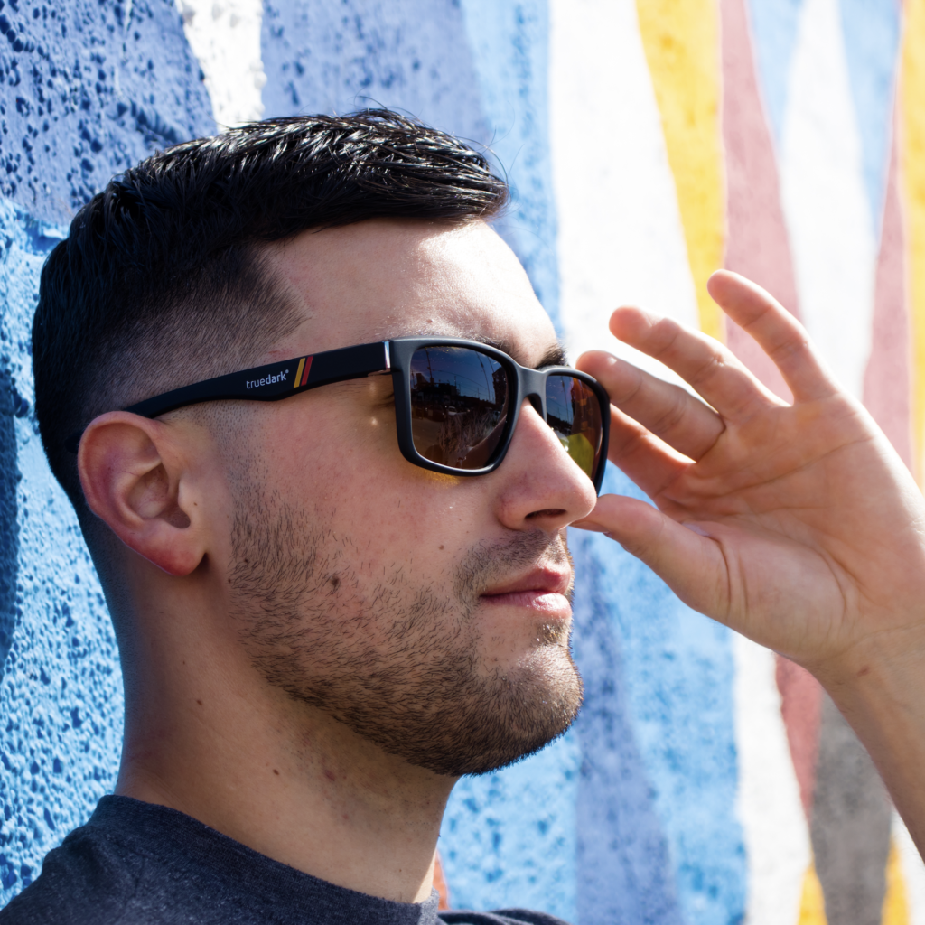 Man leaning against graffiti-ed wall wearing Daylight Transition Fairlane sunglasses