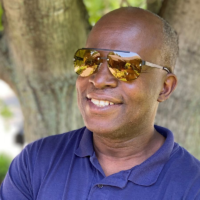 Man in purple shirt wearing TrueDark Daylights Transitional Bel-Air Aviator Sunglasses