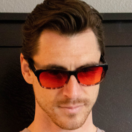 Man wearing TrueDark Dawning Black + Grey tortoiseshell red lensed glasses
