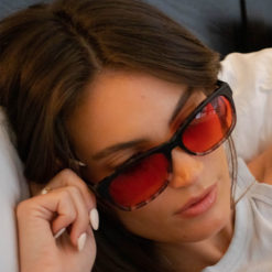 Woman wearing TrueDark Dawning Black + Grey tortoiseshell red lensed glasses